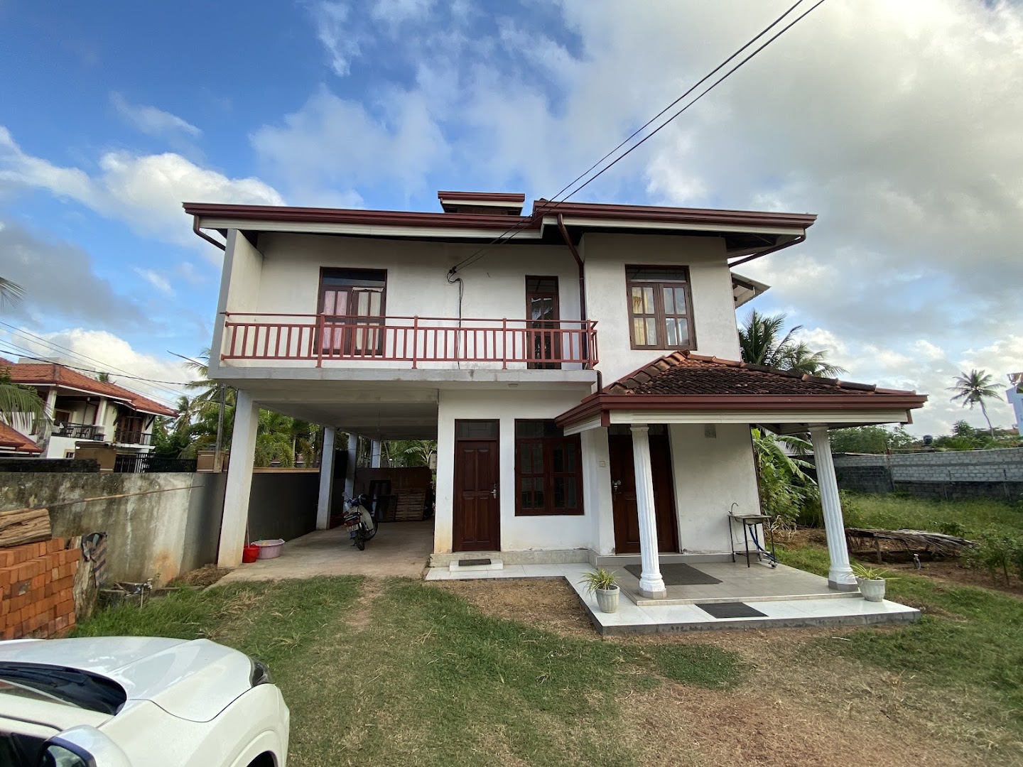 White two storey clinic building with red roof trim and timber doors